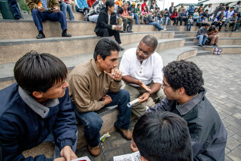 Missionaries and community members having a discussion on steps of an outdoor amphitheater.