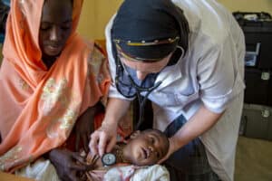 Medical healthcare worker examining a young child in a clinical setting.