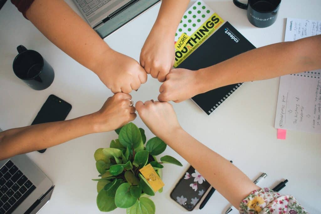 Diverse team of mission agency staff doing a fist bump for teamwork and unity.