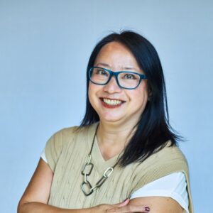 Smiling woman with glasses in a professional setting for mission organization.