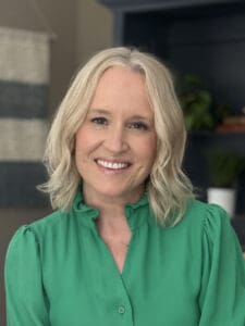 Smiling woman in green blouse, leading a communications team.