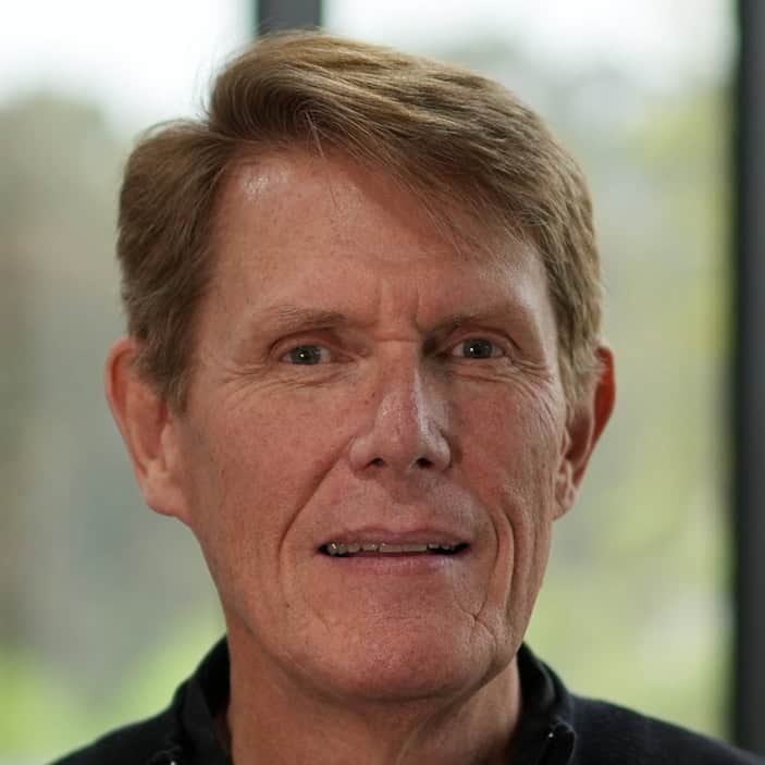 Portrait of a mature man with light brown hair and blue eyes in a professional setting.