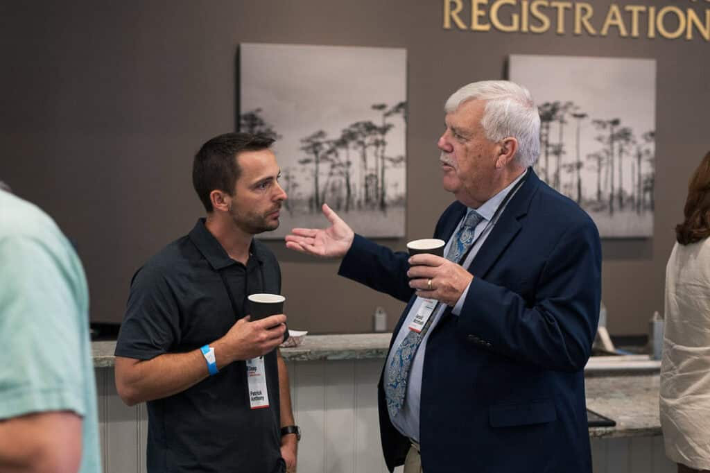 Two men engaged in conversation at Missio Nexus conference registration area.