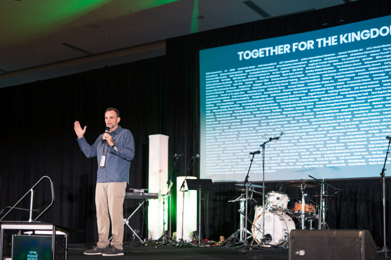 Speaker presenting at Missio Nexus conference with large screen behind.