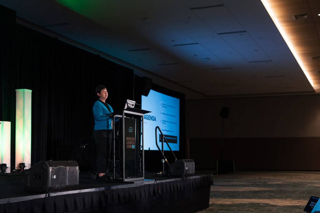 Speaker presenting at Missio Nexus conference with screen and stage setup.