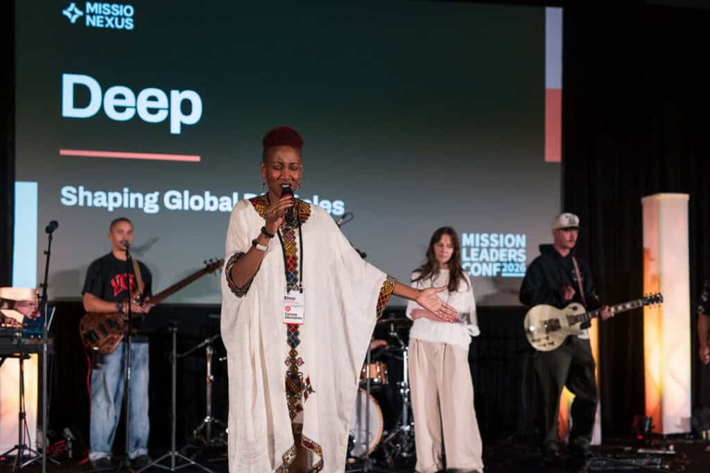 Speaker on stage at Missio Nexus conference with band in background.