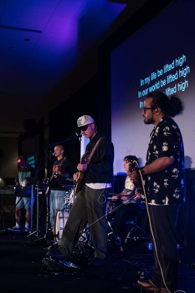 Live band performing at Missio Nexus conference with stage lighting and audience.